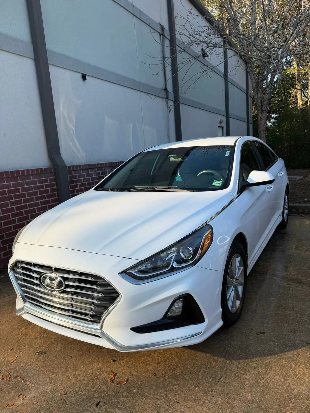 White sedan parked by a brick building after an exterior detail